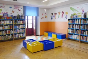 Imagen de la sala infantil donde hay estanterías con libros y mesas para niños
