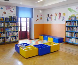 Imagen de la sala infantil donde hay estanterías con libros y mesas para niños
