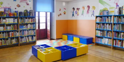 Imagen de la sala infantil donde hay estanterías con libros y mesas para niños